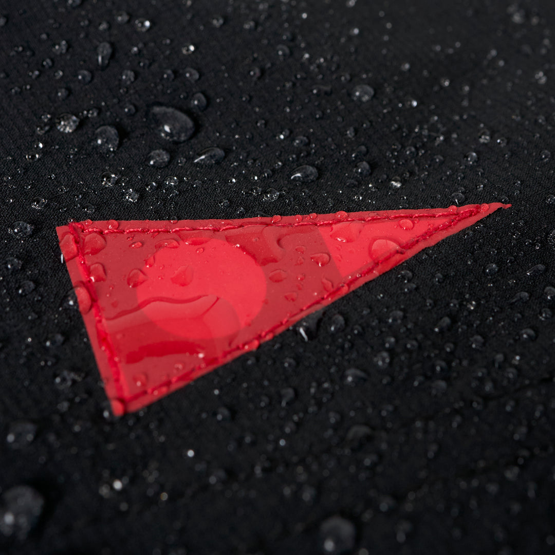 Close-up of black fabric with water droplets and a red triangular patch on the shorts.